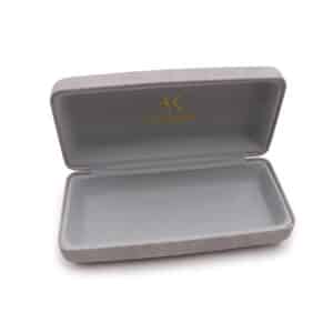 A. Kjaerbede - Sunglasses Case: A grey rectangular case with a hinged lid is open to reveal an empty interior. The inside of the lid displays a gold logo and text, echoing unique Estonian-inspired design ideas. Gate21.ee
