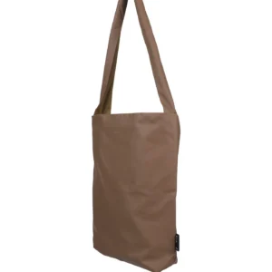 The Feel Good Bag - Beaver Fur by Tinne+mia is a brown, rectangular tote with a single long strap, smooth slightly glossy material, and a small black label on one side, displayed against a white background. Gate21.ee