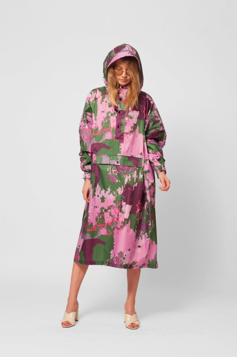 Wearing the Digi Spring hooded long-sleeve dress with a pink, purple, and green abstract floral pattern, a person stands against a plain white background—perfect inspiration for unique Tallinn shopping or your local gift shop. Light open-toe heels complete the look. Gate21.ee
