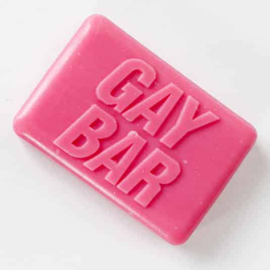 The GAY BAR - Soap is a rectangular pink bar embossed with "GAY BAR" in bold capitals on top, designed for a concept shop and photographed against a white background. Gate21.ee