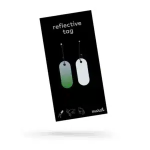 A black package labelled "Reflective Tag - Green Fade" displays two rectangular tags with ball chains on a white background. Rucksack, dog, and bicycle icons suggest its versatility—a practical Estonian design from Tallinn gift shops. Gate21.ee