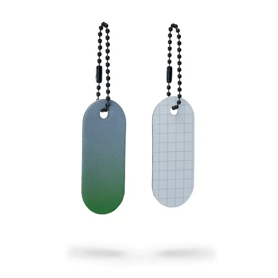 The Reflective Tag - Green Fade set includes two oval metal tags on beaded chains: the left tag transitions from green to grey, while the right is light grey with a subtle grid, both displayed on a white background. Gate21.ee