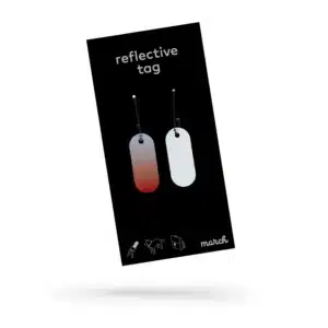 A black package labelled "Reflective Tag - Red Fade" displays two red-fade dog-tag-shaped reflective tags on ball chains. Icons of a person, bag, bike, and dog appear below with "march" in white—ideal for Tallinn shopping or as a design gift. Gate21.ee