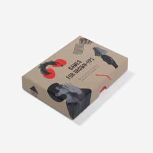 A rectangular beige box labelled Games for Grown-ups features abstract red and black graphics, curated black-and-white photos, and hints of Estonian design. The box is placed on a white surface and viewed at an angle. Gate21.ee