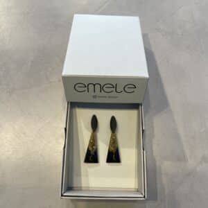 A pair of EMELE - k&otilde;rvar&otilde;ngad - K&Otilde;IK black and gold geometric earrings sits in an open white emele box on a grey surface, highlighting unique Estonian design&mdash;ideal for concept stores or gift shops. Gate21.ee