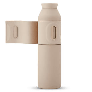 The Closca Wave Large - Sahara (600ml) is a beige cylindrical water bottle with a matching removable cup. Its minimalist Estonian design features smooth, rounded surfaces—ideal for unique Tallinn shopping or as a stylish gift shop accessory. Gate21.ee