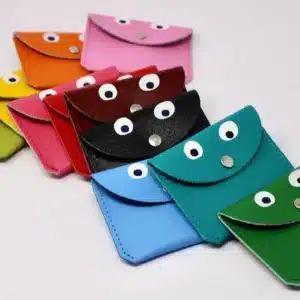 Nine Faces purses from Ark Design&rsquo;s K&Otilde;IK collection, each with two white &ldquo;eyes&rdquo; on the flap, are arranged diagonally on a plain white background. The small, colourful coin purses showcase playful Estonian design. Gate21.ee