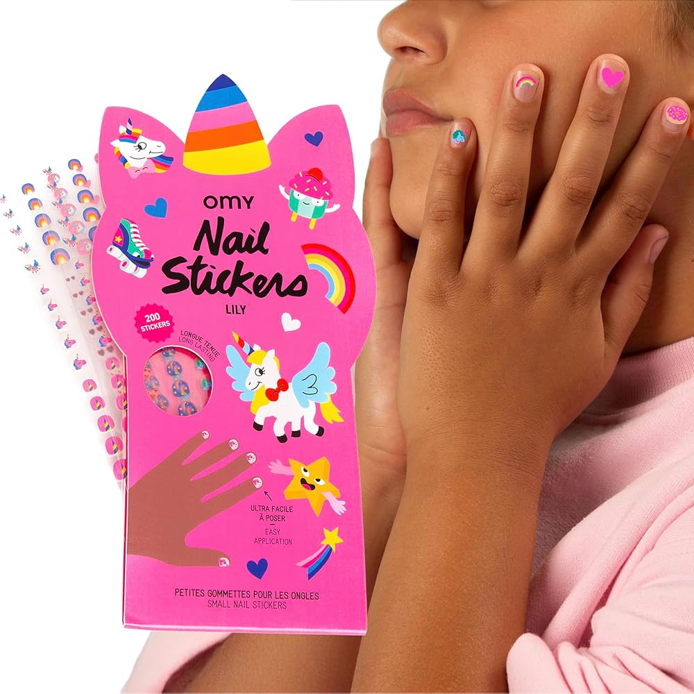 A child touches their face, showing fingernails decorated with vibrant Unicorn - Nail Stickers. In the foreground is a pink box labelled Unicorn - Nail Stickers, featuring unicorn and rainbow illustrations. Gate21.ee