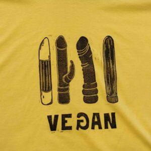 The Riivo T-shirt is a yellow tee featuring black graphics of four vegetables resembling sex toys above the word VEGAN&mdash;with a reversed G. This curated Estonian design offers bold, unique style for those seeking standout fashion statements. Gate21.ee