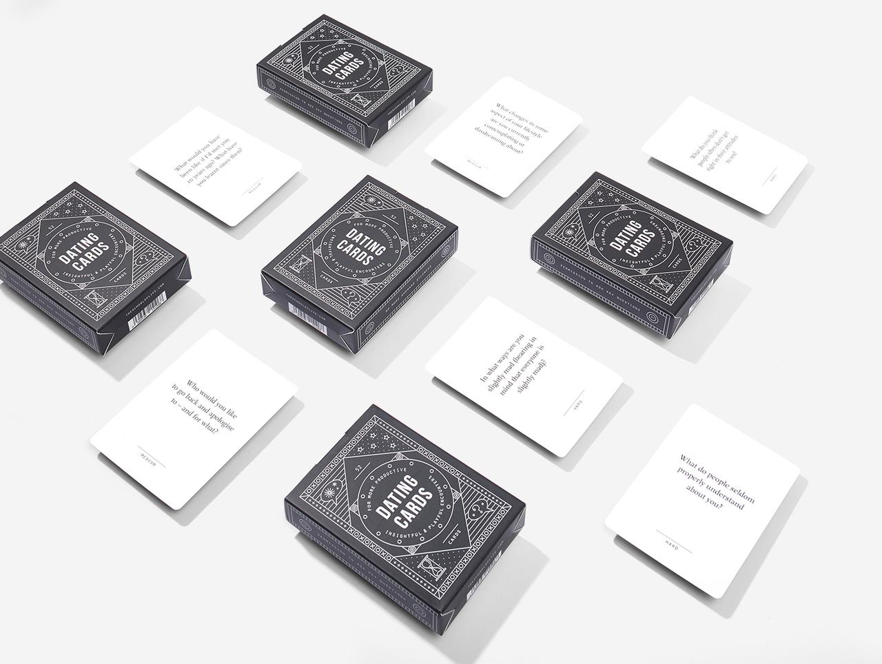 Nine black Dating Cards boxes and seven white question cards are arranged in a grid on a white surface. This modern Estonian-designed set is ideal for concept shops or as a unique present, with some card texts partially visible. Gate21.ee