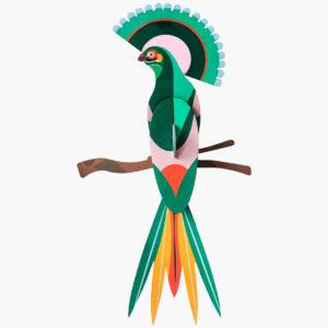 Paradise Bird Gili is a paper craft sculpture showcasing curated Estonian design. The colourful bird features vibrant green, pink, red, yellow, and orange on a brown branch, all displayed against a plain white background. Gate21.ee