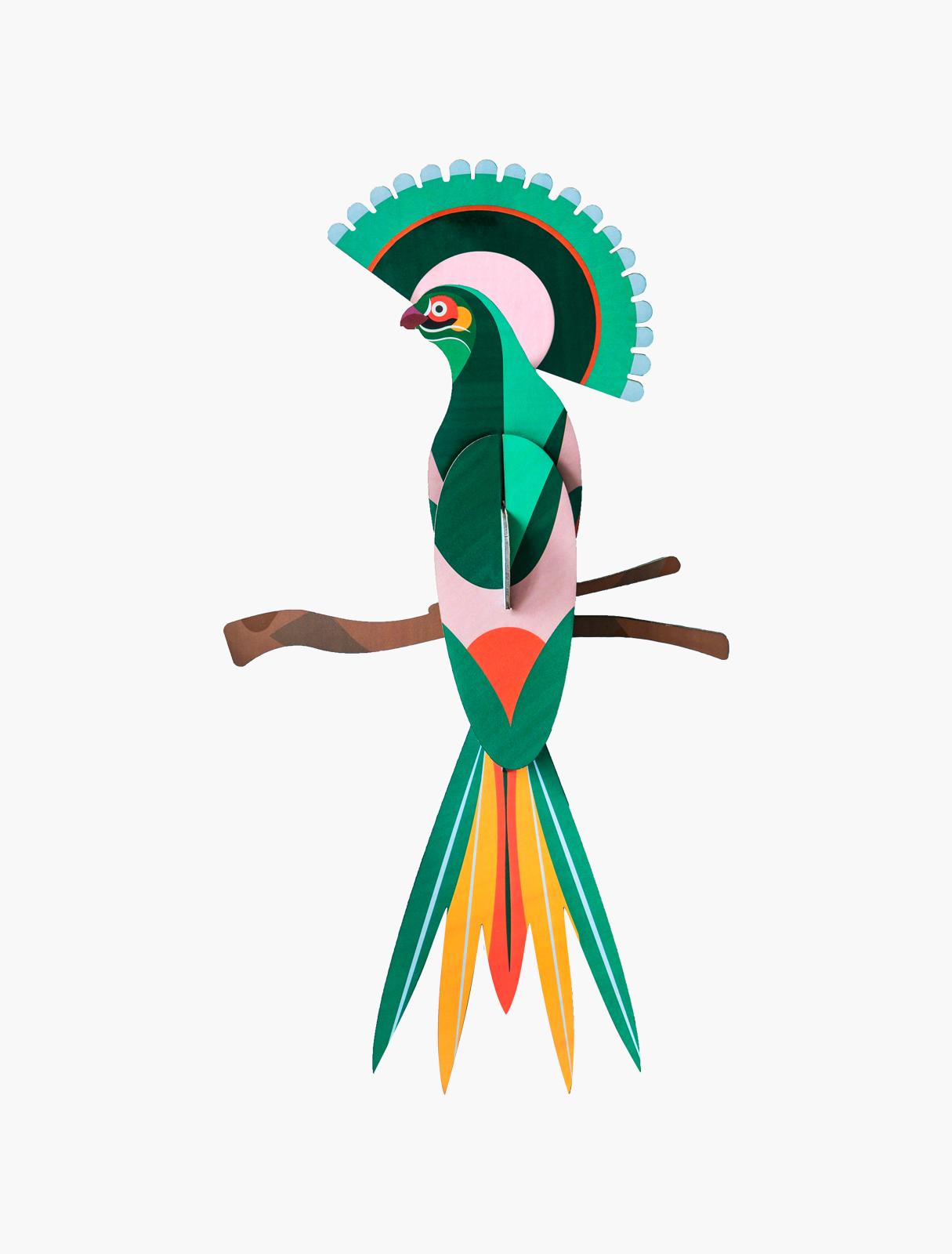 Paradise Bird Gili is a paper craft sculpture showcasing curated Estonian design. The colourful bird features vibrant green, pink, red, yellow, and orange on a brown branch, all displayed against a plain white background. Gate21.ee