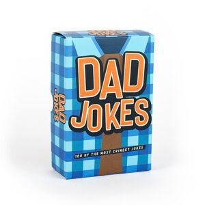 A blue and brown checked box labelled "Dad Jokes - 100 of the Best" in large orange and white letters stands upright on a white background, making it perfect for gifting or picking up during your Tallinn shopping spree. Box contains 100 cringeworthy jokes. Gate21.ee