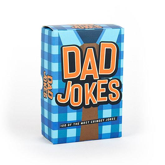 A blue and brown checked box labelled "Dad Jokes - 100 of the Best" in large orange and white letters stands upright on a white background, making it perfect for gifting or picking up during your Tallinn shopping spree. Box contains 100 cringeworthy jokes. Gate21.ee
