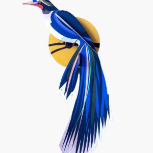 Paradise Bird Flores features a stylised paper bird with blue, purple, and white feathers perched before a yellow circle—an eye-catching piece inspired by Estonian design, perfect for adding unique flair to your gift shop. Gate21.ee