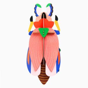The Giant Ladybird is a colourful geometric paper sculpture with pink wings, a green triangle at the top, yellow legs, and blue, brown, and black accents—a striking piece for any concept shop seeking unique decor. Gate21.ee