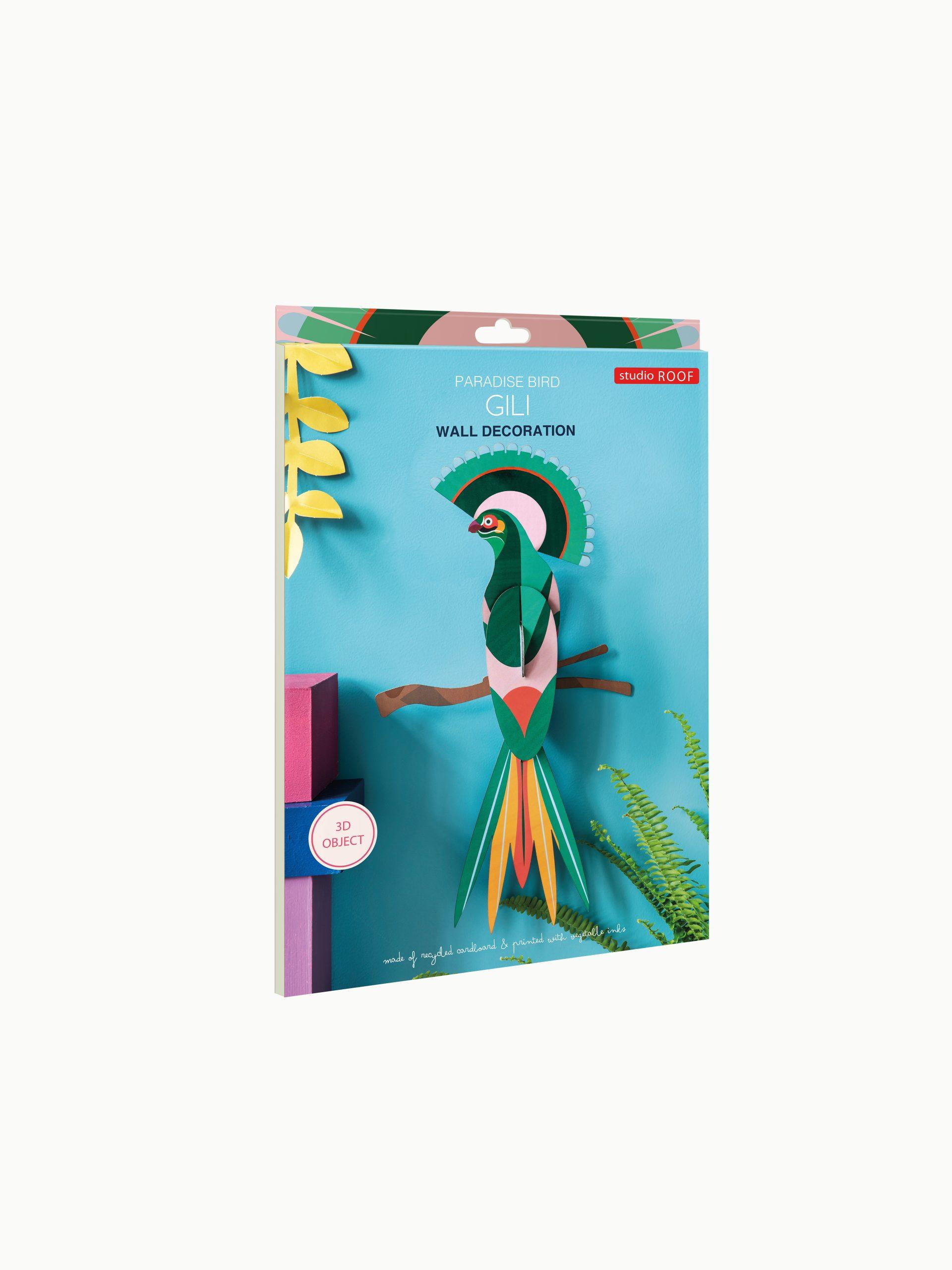 Paradise Bird Gili is a 3D wall decoration by Studio Roof, featuring a vibrant geometric paper bird on a blue background with leaves and branches. Made from recycled materials, it’s a unique Tallinn gift shop find. Gate21.ee