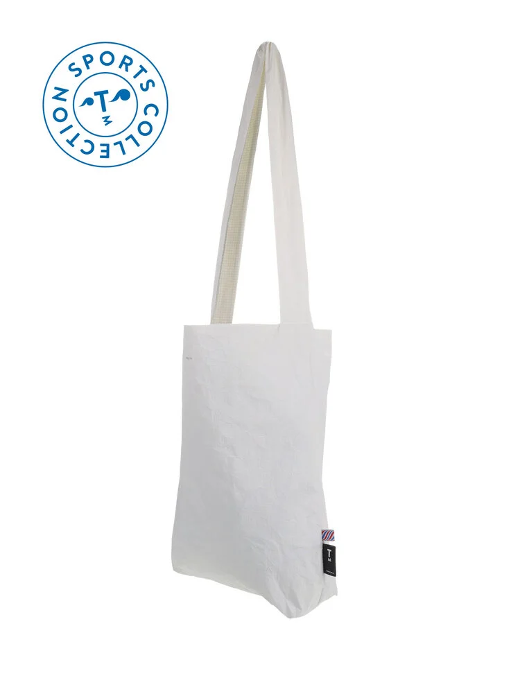 The Feel Good Sports Bag - White is displayed on a white background. It features long shoulder straps, a small black tag with coloured stripes on the side, and a blue Sports Collection logo—highlighting Estonian design. Gate21.ee