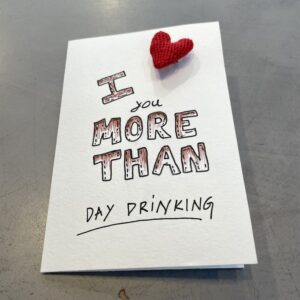The Riivo Cards - I love you more than features a white card on grey, reading &ldquo;I love you more than day drinking&rdquo; with a red knitted heart&mdash;an ideal pick for unique gift ideas from your favourite concept shop. Gate21.ee
