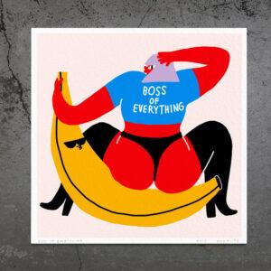 Boss of Everything - FRAMED features an abstract person with red skin in a blue “BOSS OF EVERYTHING” shirt, holding paper whilst sitting on a huge yellow banana against concrete—ideal for concept shops seeking unique art. Gate21.ee