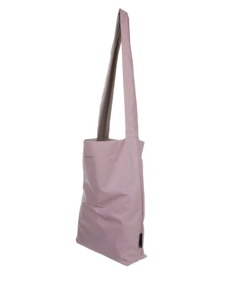 The Feel Good Bag - Rose Smoke is a light pink tote with a wide shoulder strap, shown upright at an angle highlighting its side and front. Its minimalist design makes it ideal for Tallinn shopping or gifting unique style ideas. Gate21.ee