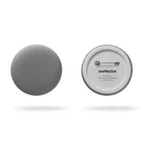 Two views of the Double – Metallic Pink button badge: the front features a matt metallic pink finish, while the back displays a metal pin fastener with oreflector branding and designer details—a subtle touch of Estonian design. Gate21.ee