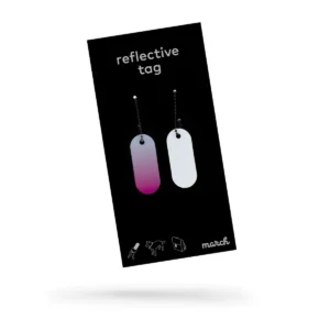 The Reflective Tag - Pink Fade comes in black packaging and features two oval tags with ball chains: one tag fades from pink to white, the other is white with a grid pattern. Icons and the brand name "march" appear at the bottom—ideal for creative concepts. Gate21.ee