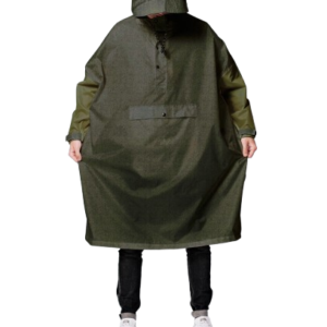 A person wearing Herringbone—a loose, hooded, olive-green poncho with a large front pocket—stands facing forwards in dark trousers and white trainers, capturing curated style inspired by Tallinn shopping. Gate21.ee