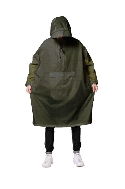 A person wearing Herringbone—a loose, hooded, olive-green poncho with a large front pocket—stands facing forwards in dark trousers and white trainers, capturing curated style inspired by Tallinn shopping. Gate21.ee