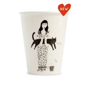 The Black Cat Cups feature a black and white illustration of a woman holding a cat, beside a small potted plant. Accented with a red "NEW" heart label—an ideal pick for gift shops looking for unique finds. Gate21.ee