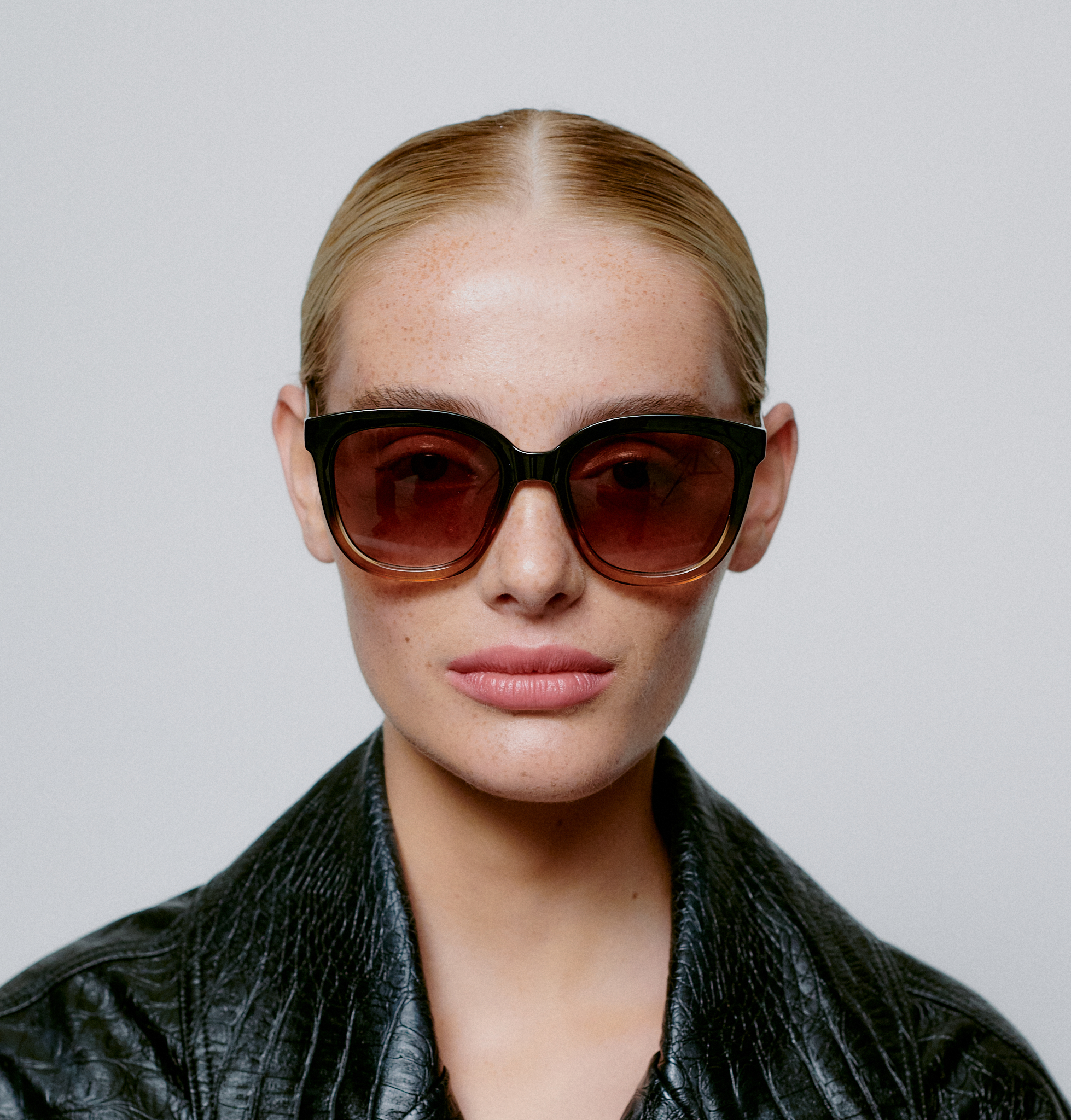 Wearing BILLY - Black Brown Transparent sunglasses and a black textured jacket, a person with slicked-back blonde hair showcases curated style against a plain, light background. A neutral expression hints at Tallinn shopping or unique fashion ideas. Gate21.ee