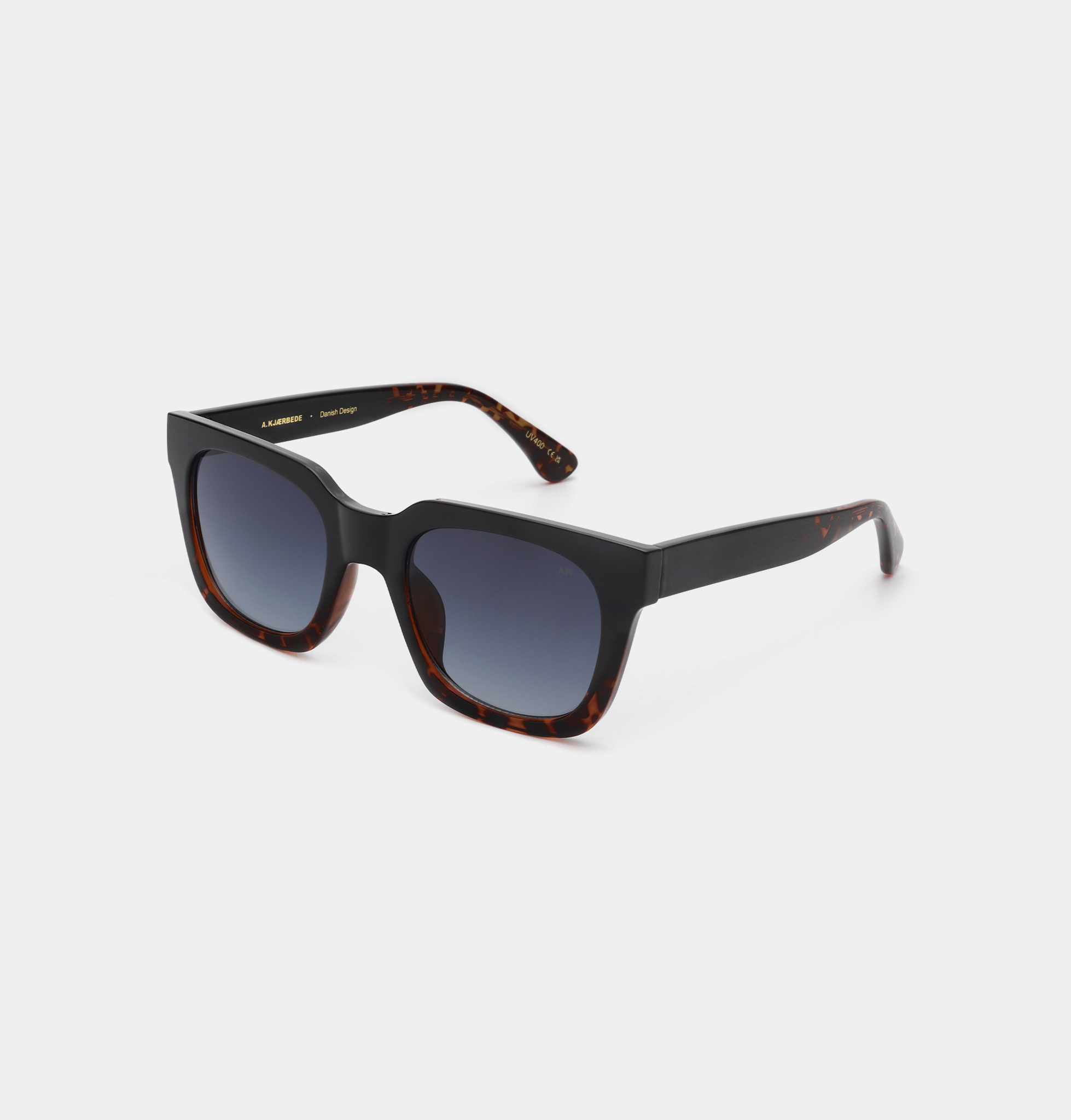 The NANCY - Black Demi Tortoiseshell sunglasses feature square frames in black and tortoiseshell, dark gradient lenses, and angular arms—ideal for curated, unique gifts. Displayed on a light grey background. Gate21.ee