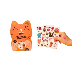 A hand holds three sheets of Kawaii - Temporary Tattoos with cute, colourful designs beside a cat-shaped package on a white background—ideal for Tallinn shoppers or fans of Estonian design. Gate21.ee