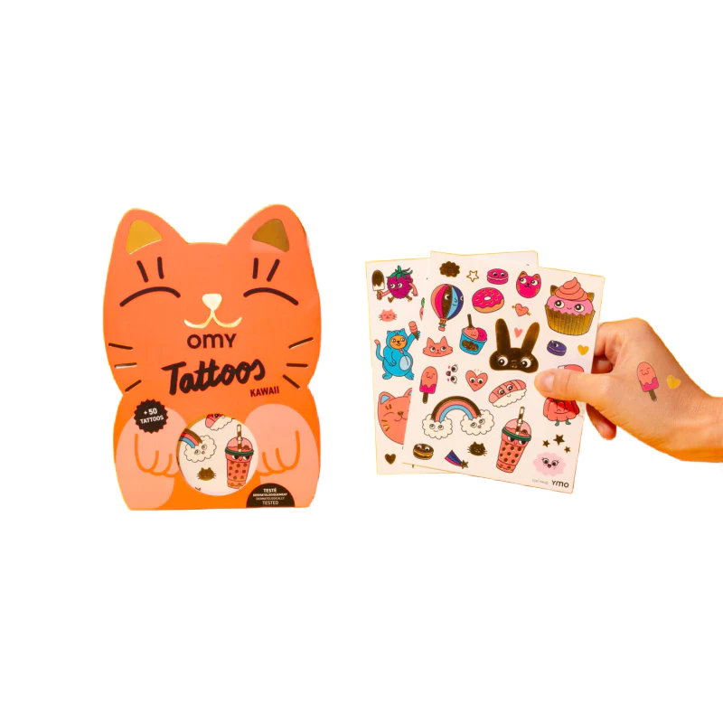A hand holds three sheets of Kawaii - Temporary Tattoos with cute, colourful designs beside a cat-shaped package on a white background—ideal for Tallinn shoppers or fans of Estonian design. Gate21.ee