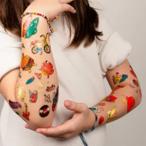 A person in a white shirt displays both forearms covered with Dinos - Temporary Tattoos, featuring playful and unique Estonian designs like food, guitars, bicycles, and animals. The person's face is not visible. Gate21.ee