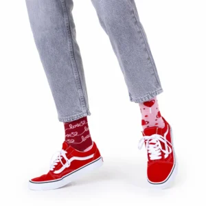 Wearing the Love Story light grey jeans, red and white trainers, and mismatched socks—one red with "love" and one pink with hearts—this look offers unique Tallinn shopping ideas against a crisp white backdrop. Gate21.ee