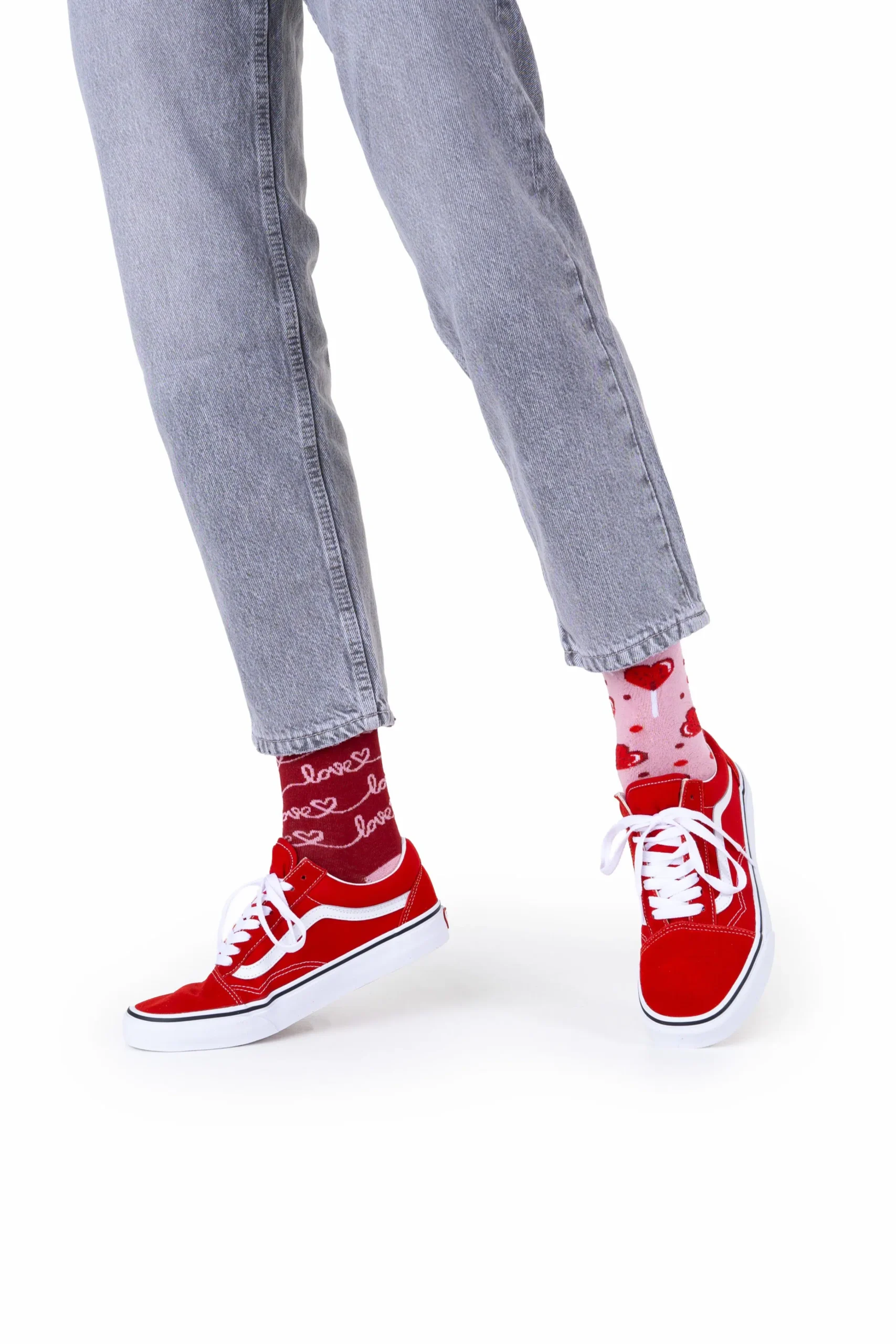 Wearing the Love Story light grey jeans, red and white trainers, and mismatched socks—one red with "love" and one pink with hearts—this look offers unique Tallinn shopping ideas against a crisp white backdrop. Gate21.ee