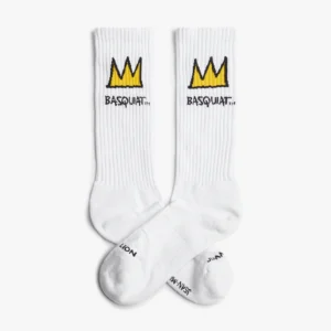The Basquiat Crown - Athletic socks are white crew socks with a yellow crown above BASQUAT™ embroidered in black, plus black text near the toes on the soles—perfect for concept shop fans or Tallinn shopping enthusiasts. Gate21.ee