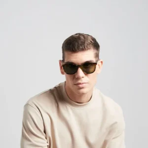 A man with short brown hair wears "Arroyo" Tortoise Sunglasses and a beige crew-neck shirt, styled with curated Estonian design, looking at the camera against a plain light grey background. Gate21.ee