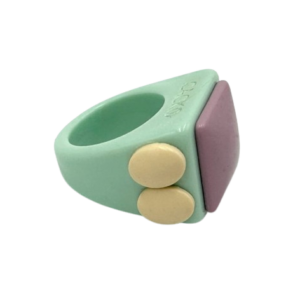 The Arczi - Ring is a chunky, pastel accessory with a mint green band, two round yellow side buttons, and a flat square lavender accent—an eye-catching piece of Estonian design ideal for unique gift shop finds. Gate21.ee