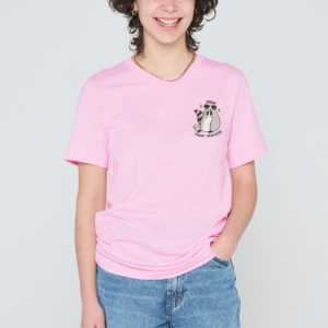A person with curly hair smiles at the camera, wearing a light pink Love Me Worm T-shirt and blue jeans, with one hand in their pocket. Gate21.ee