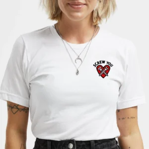 A blonde person with tattoos and a necklace wears the Screw You Embroidered T-Shirt - White, featuring a small embroidered broken heart and “SCREW YOU” on the left chest—an example of curated Estonian design. Gate21.ee