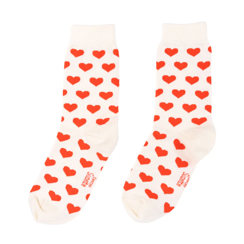 Hearts - Cotton Socks: A pair of white crew socks featuring evenly spaced red hearts, ideal for those wanting unique finds whilst shopping in Tallinn. The socks are displayed flat, toes facing forwards. Gate21.ee