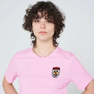 A person with short, curly brown hair models the Jam Jar T-Shirt - Pink, featuring a small jar graphic and "empty" on the chest, against a plain light backdrop—ideal for a stylish day out Tallinn shopping or exploring concept shops. Gate21.ee