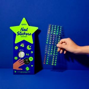 A hand displays a sheet of colourful Glow in the Dark - Nail Stickers beside its blue and neon green packaging, featuring glow-in-the-dark designs—perfect for those seeking creative ideas from concept shops or Estonian-inspired products. Gate21.ee