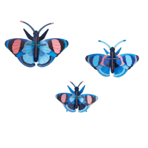 The Peacock Butterflies - Set of 3 features blue butterflies with black, pink, and light blue patterns arranged on a white background in a modern Estonian style—one at the top left, two grouped on the lower right. Gate21.ee