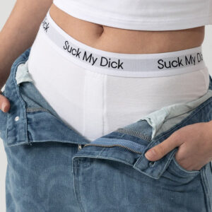 A person wears light blue jeans unbuttoned to reveal Suck It Boxers - White, featuring a bold waistband print, styled with a white crop top for an edgy concept shop look. Gate21.ee