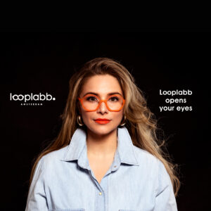 A woman with long blonde hair wears FAUST - Black spectacles and a light blue button-up shirt, facing the camera against a black background. White text reads: Looplabb opens your eyes to Estonian design and unique ideas at Looplabb Amsterdam. Gate21.ee