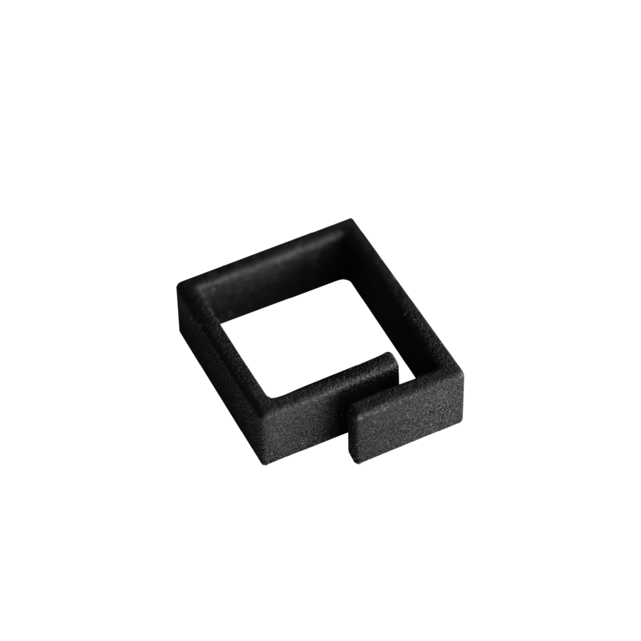 A black, square-shaped plastic object with an open side and a short protruding tab, reminiscent of unique ideas often found in Tallinn shopping concept shops, placed on a plain white background. Gate21.ee