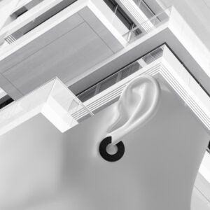 A monochrome image shows a close-up of a mannequin’s ear with a circular earring in the foreground, set against modern geometric balconies—perfect inspiration for unique ideas found during Tallinn shopping adventures. Gate21.ee